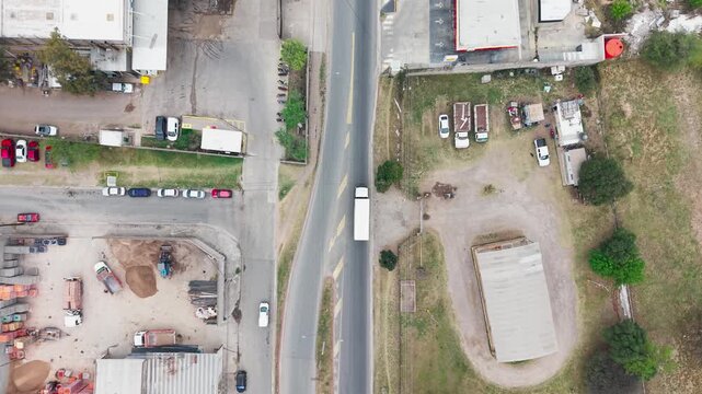Dron sigue a un cami&oacute;n blanco en vista cenital por una calle de zona industrial