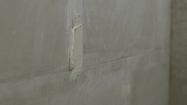 Wall Repair Filling Cracks. Close up of a handyman using a putty knife to apply joint compound over fiberglass mesh tape to repair a long vertical crack in a residential interior wall