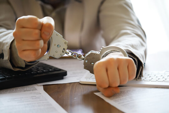 stressed out businessman hands bothered with handcuffs suffering at custody for concept of suspicious business, hostage or corporate justice