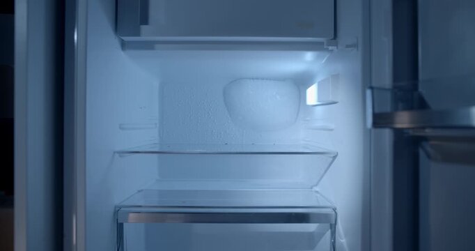 Cinematic slider push-in toward an empty opened refrigerator, emphasizing the lack of food and household essentials. Powerful visual concept for poverty, hunger, food insecurity, financial hardship.