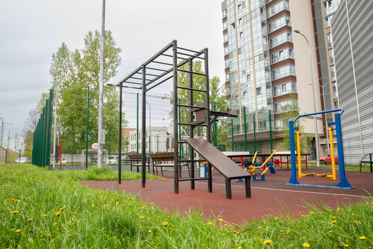 Outdoor calisthenics workout complex with rubber safety flooring in residential courtyard. Street workout and bodyweight fitness. Outdoor fitness and community recreation.
