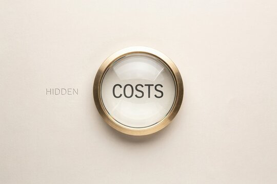 A magnifying glass revealing the word costs next to hidden text on a beige surface.
