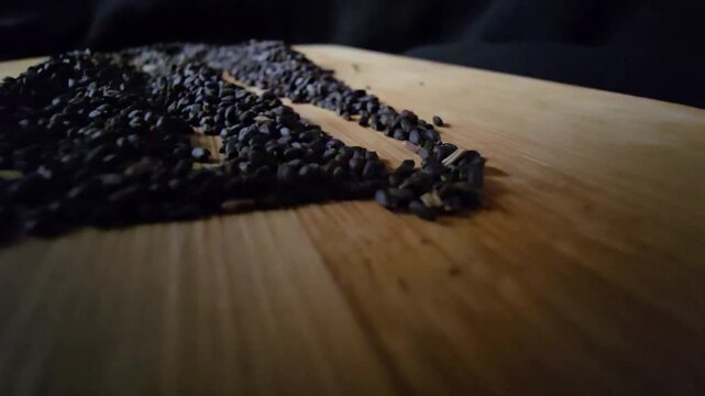 Cinematic macro video of organic black basil seeds artfully arranged on a rustic wooden cutting board. Great for healthy eating, cooking ingredients, and natural wellness projects.   