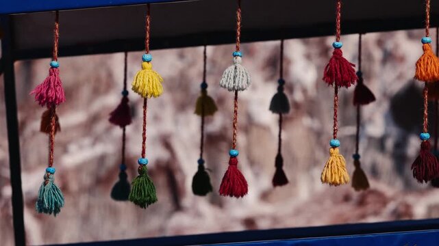 Colorful decorative yarn tassels hanging and gently swaying, traditional oriental tribal handmade hanging ornaments, Traditional Persian decoration used in transportation and interior design.