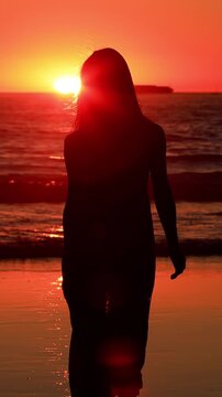 Attractive Asian woman enjoys a walk on the beach at sunset in Southern California. Slow Motion. Vertical Video.