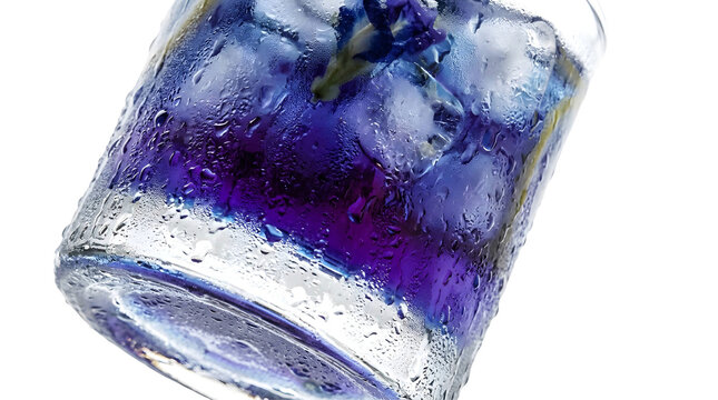 Glass of cold blue butterfly pea flower tea with ice cubes and heavy water condensation drops isolated on transparent background. 