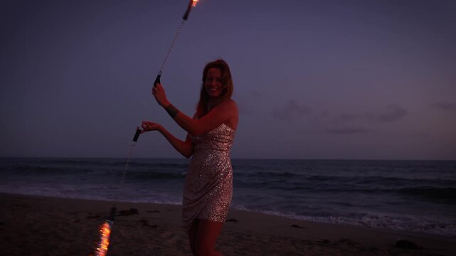 Attractive woman fire dancer spinning flames at the beach. Slow Motion.