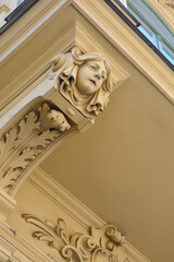 A detailed low angle view captures a beige Art Nouveau architectural corbel featuring a carved female head mascot and floral ornaments beneath a balcony. © nahhan