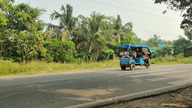 Electric Toto rickshaw driving along the busy National Highway 117 in West Bengal, India
