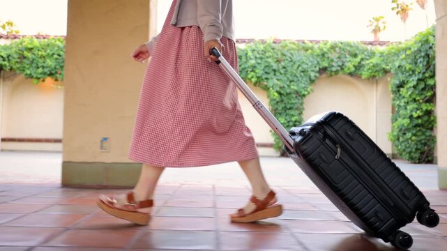 Asian woman walking through a train station with her suitcase.