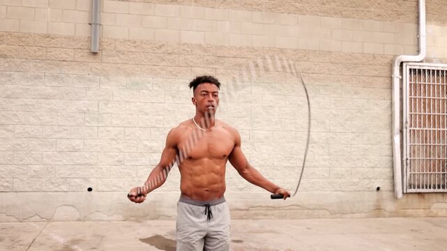 Athletic African American man with a disabled left hand working out with a jump-rope in a warehouse area near downtown Los Angeles.