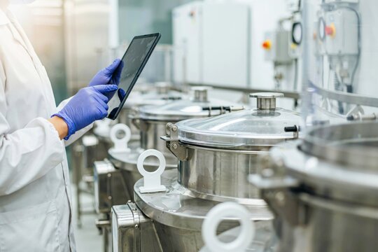 Scientist using a digital tablet to monitor industrial food processing or pharmaceutical equipment