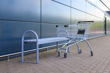 Empty shopping cart outside a modern supermarket. Concerning consumer demand and the retail economy. © yaviki