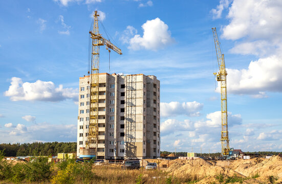 Two yellow tower cranes at a construction site. Construction of a residential apartment building.