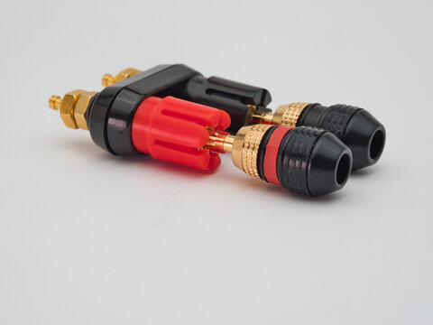 Banana Plug Connectors - Pair of audio banana plug connectors with gold-plated tips on a binding post adapter, isolated on a clean white background.
