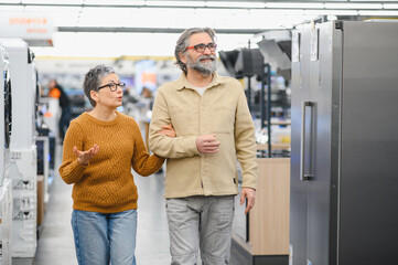 Obraz na płótnie Canvas Senior couple choosing refrigerator in appliance store