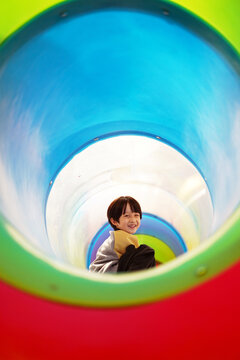 Chinese boy plays inside a playground tube.