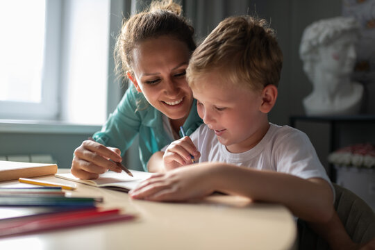 Cheerful woman drawing with boy at home