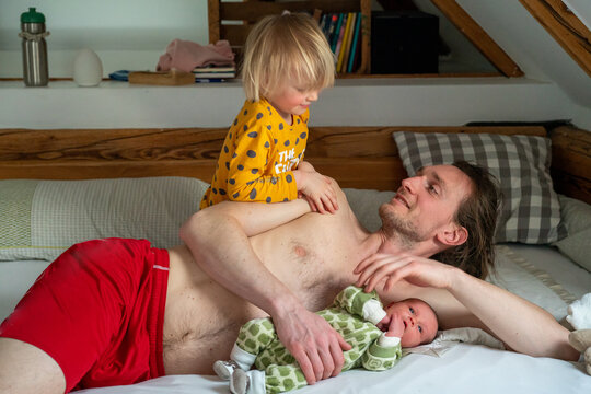 A dad with his two baby girls lying on a bed