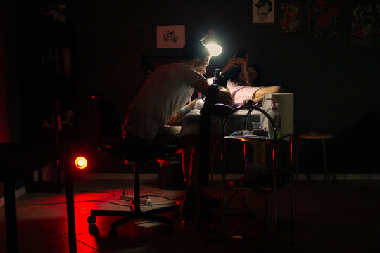 Tattooing process in dark studio