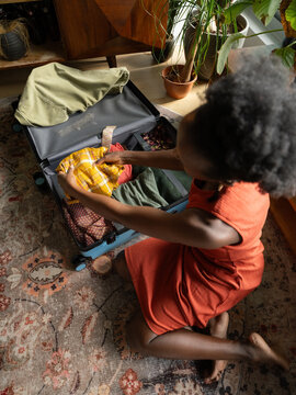 Woman packing clothes into suitcase while preparing to travel