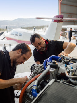 Focused mechanics repairing airplane engine together