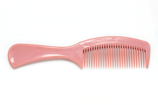 Pink plastic hair comb isolated on a plain white background with a simple pink hair comb for daily
