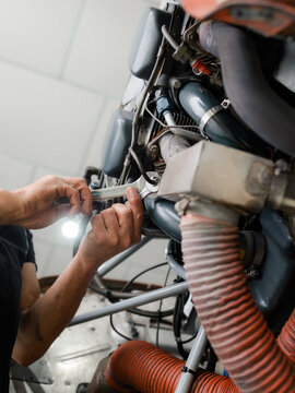 Mechanic Works on Engine With Tools in Workshop During the Day