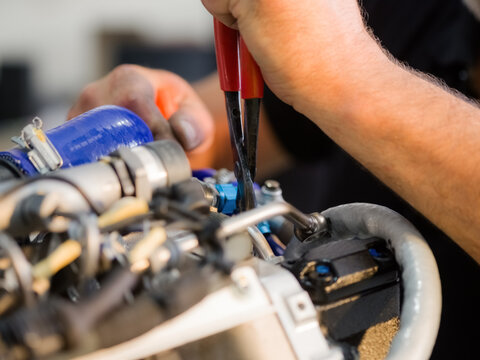 Mechanic Works on Engine With Tools in Workshop During Daytime