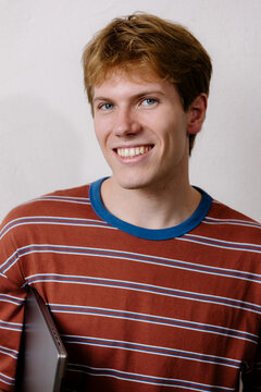 Studio portrait of a confident freelancer holding a laptop, smiling.
