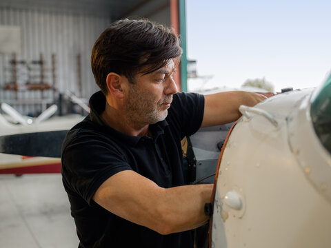 Candid mechanic is repairing plane engine