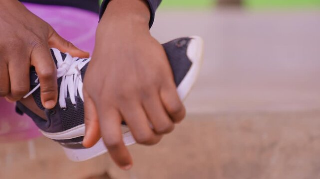 Hands tie laces for sports sneaker. Close up shows fingers working with white shoelaces and dark mesh fabric of running shoes. Background blurred focus on manual dexterity