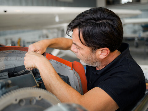 Man Works on Aircraft Engine at Maintenance Facility in Daylight