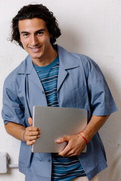 Cheerful freelancer smiling at the camera with a computer.