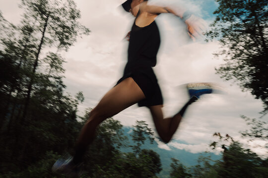 Runner Leaps Across a Forest Trail During a Cloudy Day