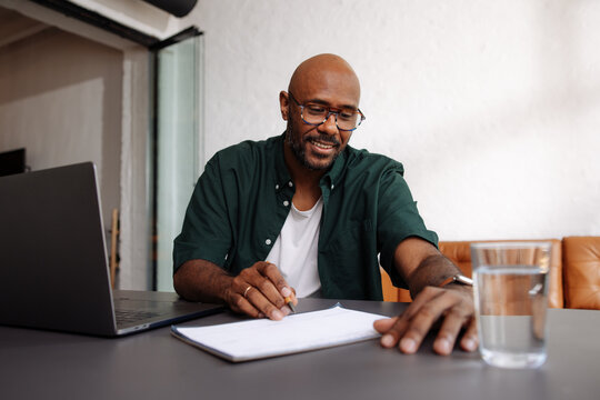 Smiling Professional Man Signing Documents at Home Office