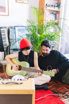 Couple playing acoustic guitar in home studio