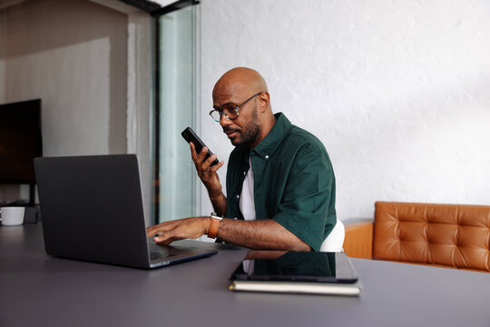 Remote Worker Using Laptop and Smartphone in Office