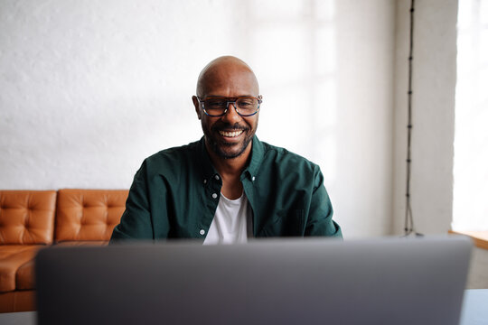 Smiling Man Working Remotely on Laptop in Home Office