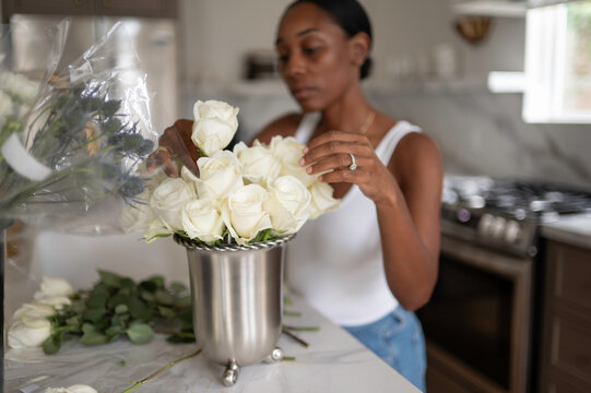 Woman Arranging White Roses in a Vase in a Kitchen