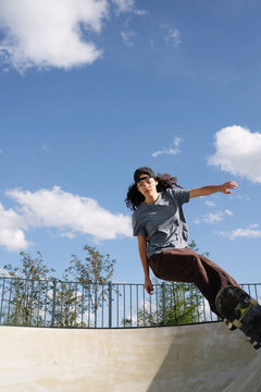 Skateboarder rides a ramp in a skatepark during a sunny day