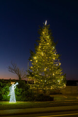 Fototapeta premium Chvalovice Christmas tree and angel illuminating holiday evening