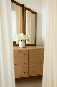 Decorative Dresser With Mirrors and Flowers in a Bright Room