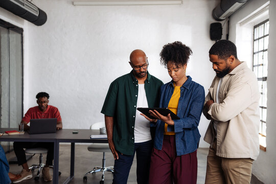 Diverse Team Reviewing Tablet in Modern Office