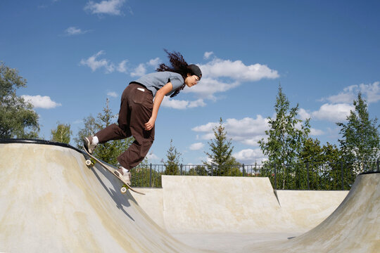 Skateboarder rides a ramp in a skatepark during a sunny day