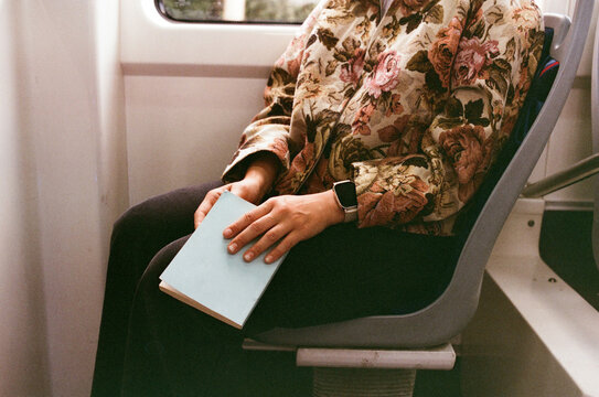 Woman holding a book while sitting at public transport