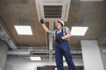 Obraz na płótnie Canvas Hvac technician installing air conditioning unit in building under construction