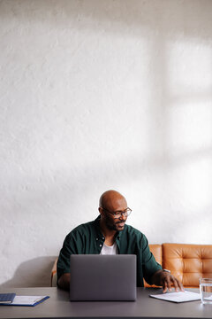 Smiling Man Working Remotely on Laptop in Home Office