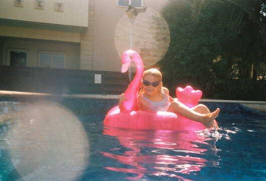 Girl Enjoys Floating in Pool on Pink Flamingo