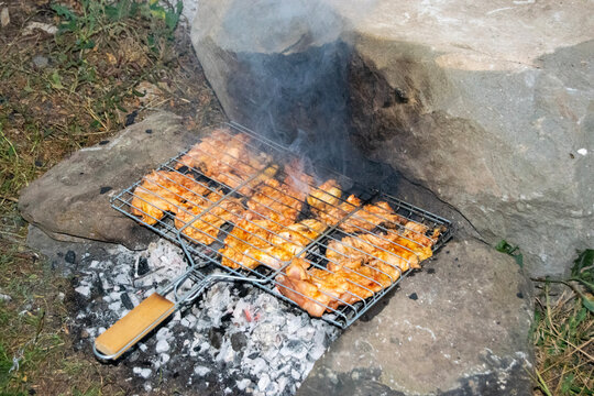 Chicken Meat Cooking On Barbecue Wire Over Embers Between Stones